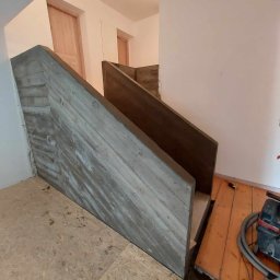 Haustechnik REMONTY I WYKOŃCZENIA Andrzej Dychus - Surowe betonowe schody z drewnianymi elementami w trakcie budowy, widoczne narzędzia i niezabezpieczona podłoga.