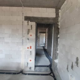 Electro-Safe Adam Jackowski - Surowy stan budynku w Olsztynie z widoczną instalacją elektryczną w peszlach na podłodze i przygotowanymi punktami na ścianach z białego bloczka.