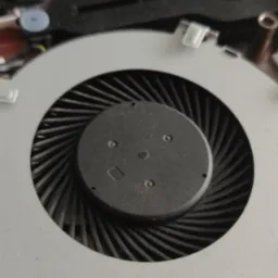 Wnętrze laptopa marki ASUS z widocznym wentylatorem chłodzącym procesor, z bliska, z widoczną naklejką z kodem QR.