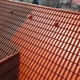 Clean-Dach Mariusz Ciesielski - Częściowo wyczyszczony dach z czerwonej dachówki ceramicznej, widoczne kominki wentylacyjne, kontrast między czystą a zabrudzoną powierzchnią.