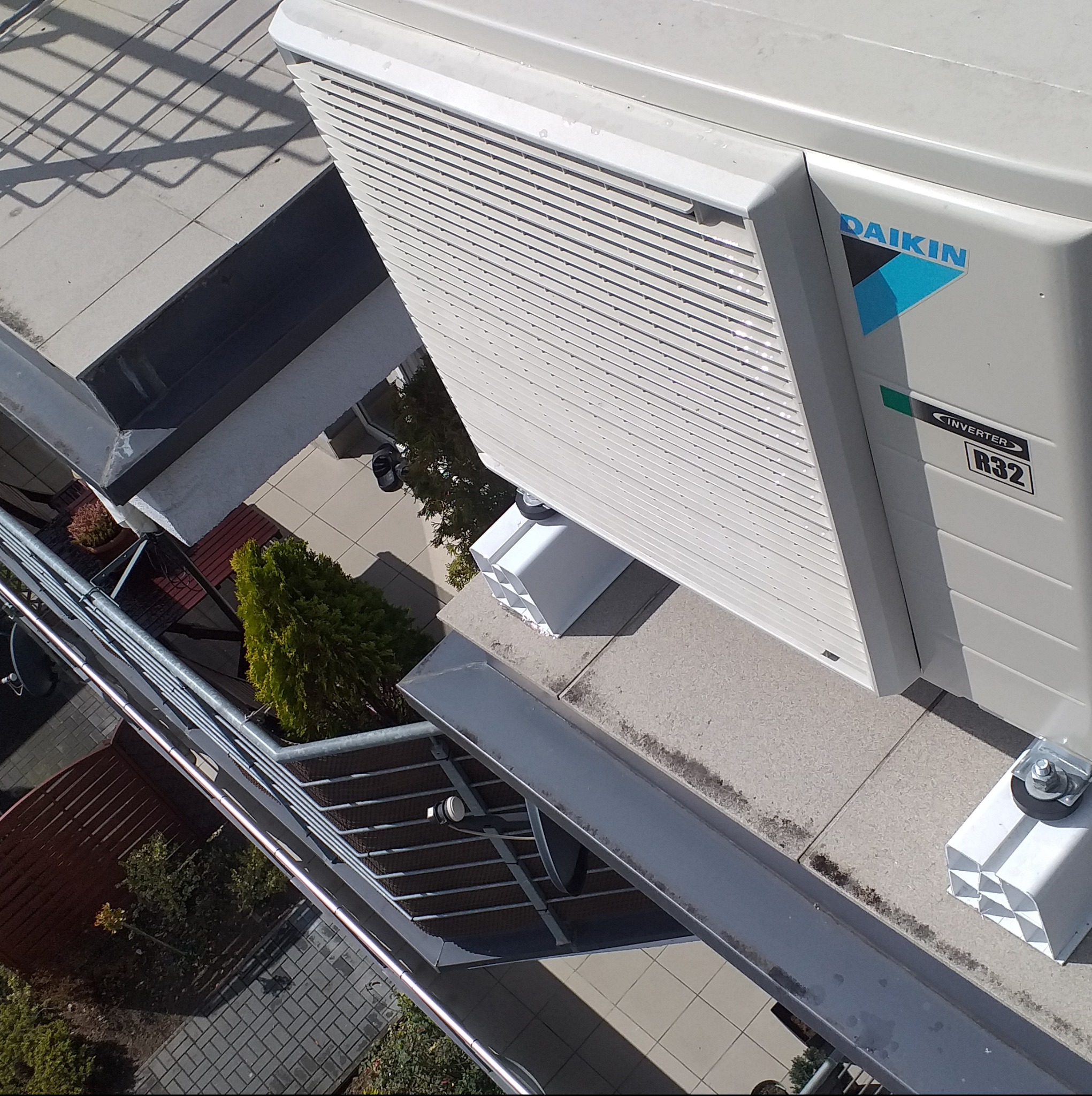 Zewnętrzna jednostka klimatyzacji Daikin zamontowana na dachu budynku, widok z góry, z widocznym logo i oznaczeniem R32.