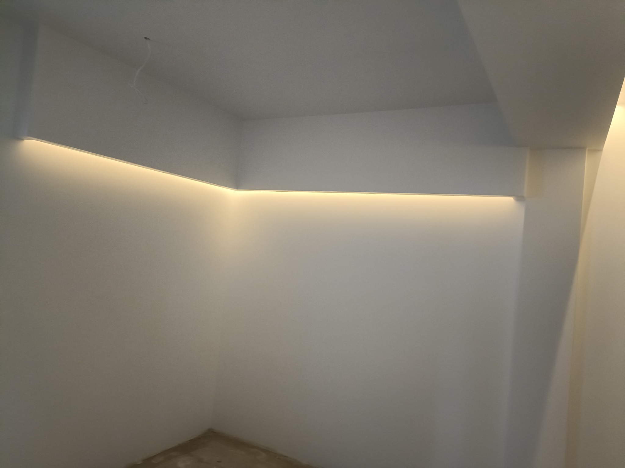 Wrocław: Widok na świeżo wykończone wnętrze z oświetleniem LED wzdłuż sufitu, ściany pomalowane na biało, widoczny fragment surowej podłogi przed dalszymi pracami.