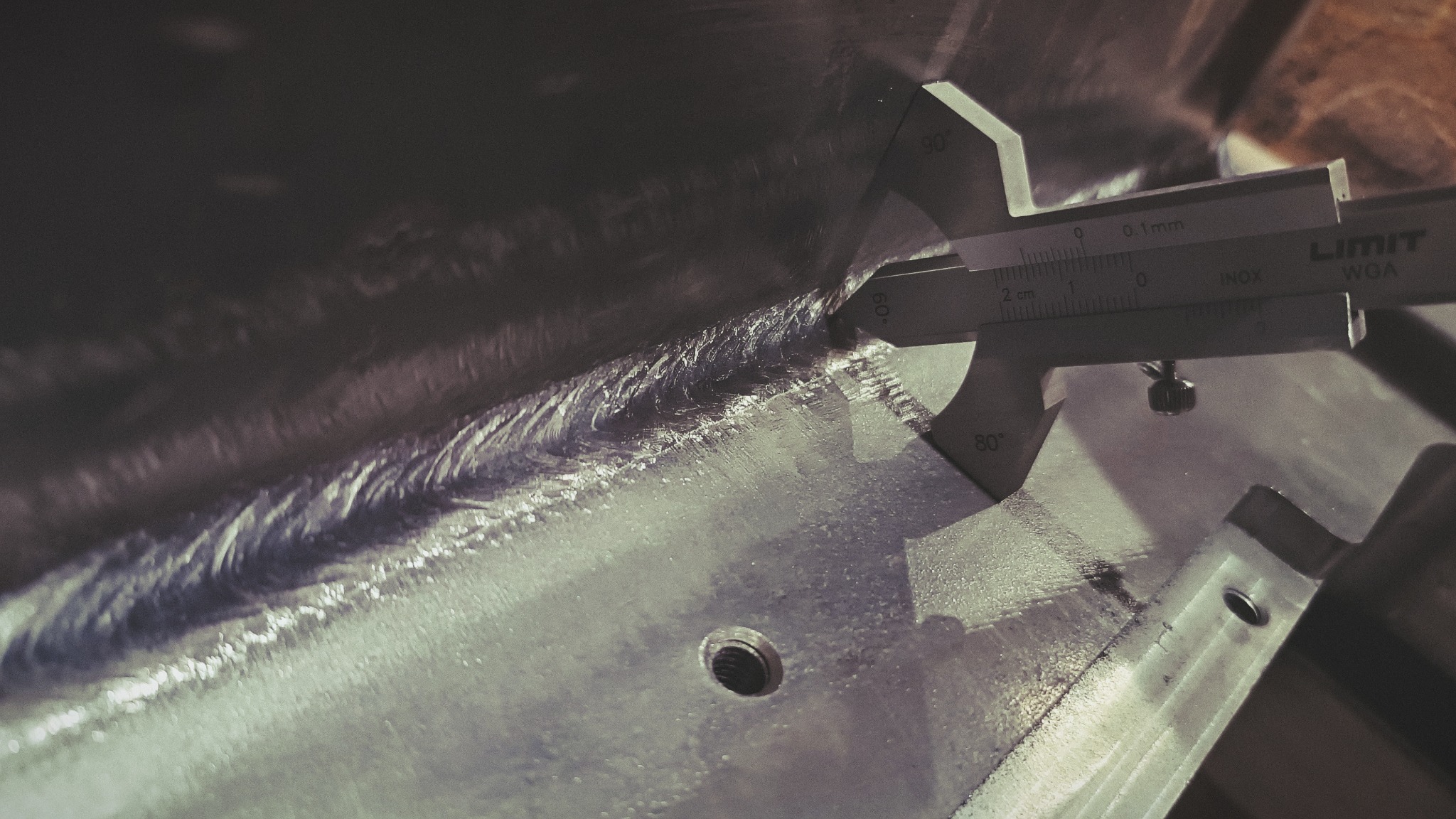 Pomiar spoiny suwmiarką LIMIT INOX na metalowej konstrukcji, widoczny otwór montażowy.