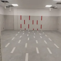 Wykończone pomieszczenie biurowe z szarą podłogą w płytkach z białymi paskami, szare ściany z czerwonymi akcentami, biały sufit z kwadratowymi lampami i widocznymi elementami wentylacji.