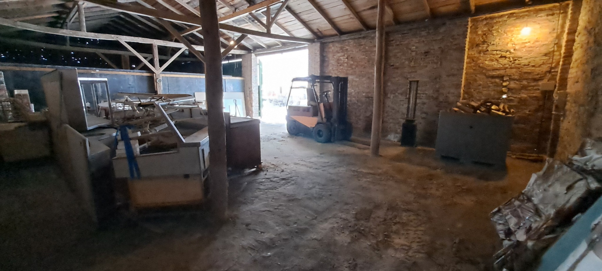 Wnętrze magazynu z wózkiem widłowym w tle i starymi meblami sklepowymi w części hali