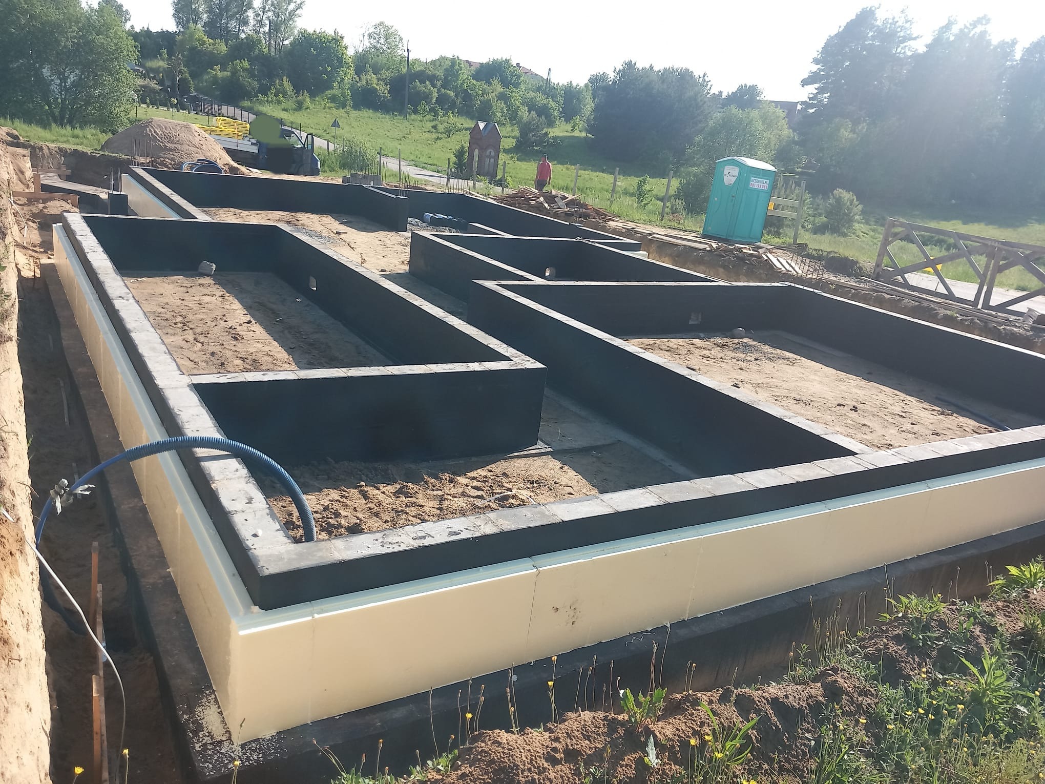 Zarys fundamentów domu jednorodzinnego w miejscowości Linia, z widoczną izolacją termiczną i hydroizolacją, przygotowany do dalszych prac budowlanych.