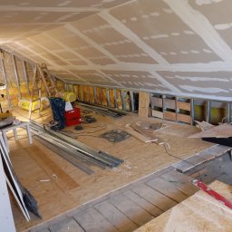 Grzegorz Kurek - Poddasze w trakcie adaptacji: widoczne ocieplenie, stelaż z profili, płyty OSB na podłodze, narzędzia i materiały budowlane. Prace wykończeniowe w toku.