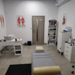 Gabinet z szarym stołem do masażu, plakaty anatomiczne na ścianach, biurko z laptopem i białe meble. Widoczny czarny dywanik i krzesło na kółkach.