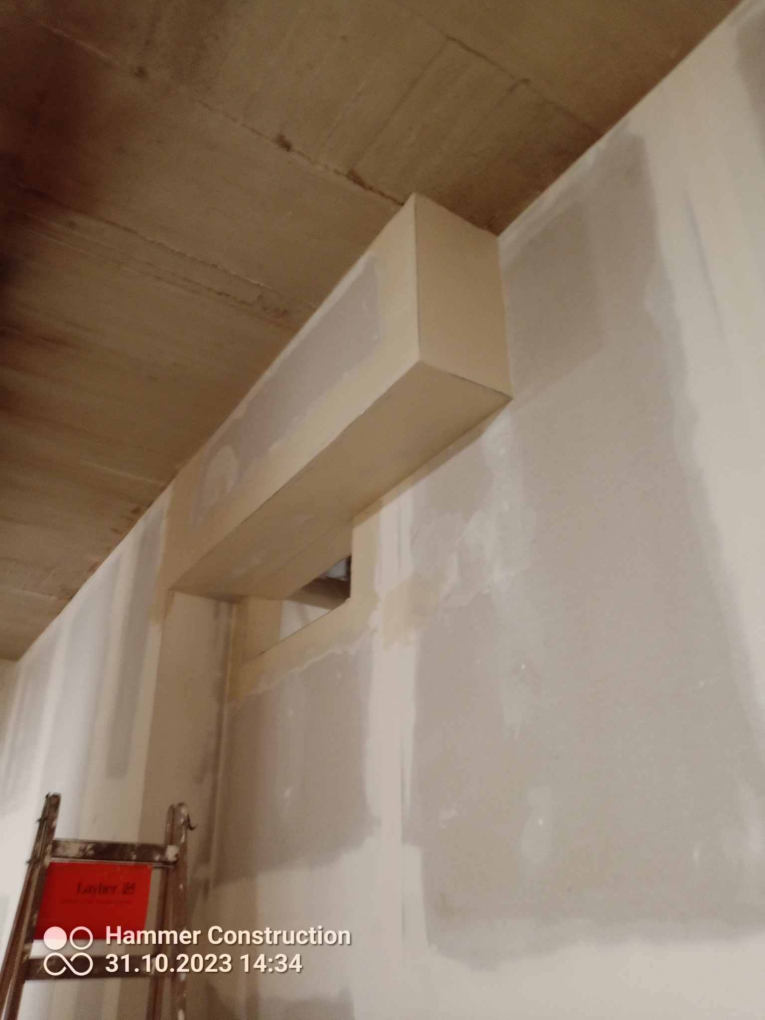 Szpachlowanie ścian i sufitu podwieszanego, widoczne ślady szpachli i drabina w rogu