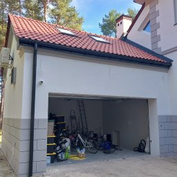 L.i.n.budservis - Nowo wybudowany garaż z czerwoną dachówką i jasną elewacją, widoczny bałagan wewnątrz, drabina i rowery.