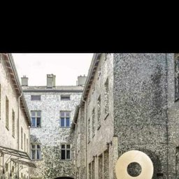 CICH-BUD CEZARY CICHOSZ - Szary budynek z cegły z dużą ikoną lokalizacji na pierwszym planie, ludzie w tle.