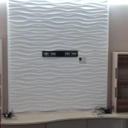 Nowoczesna ściana z paneli 3D w odcieniach bieli, z zamontowanym uchwytem na telewizor i gniazdkiem elektrycznym, nad niską szafką RTV z zaokrąglonymi frontami, uzupełniona o dekoracyjny żyrandol.