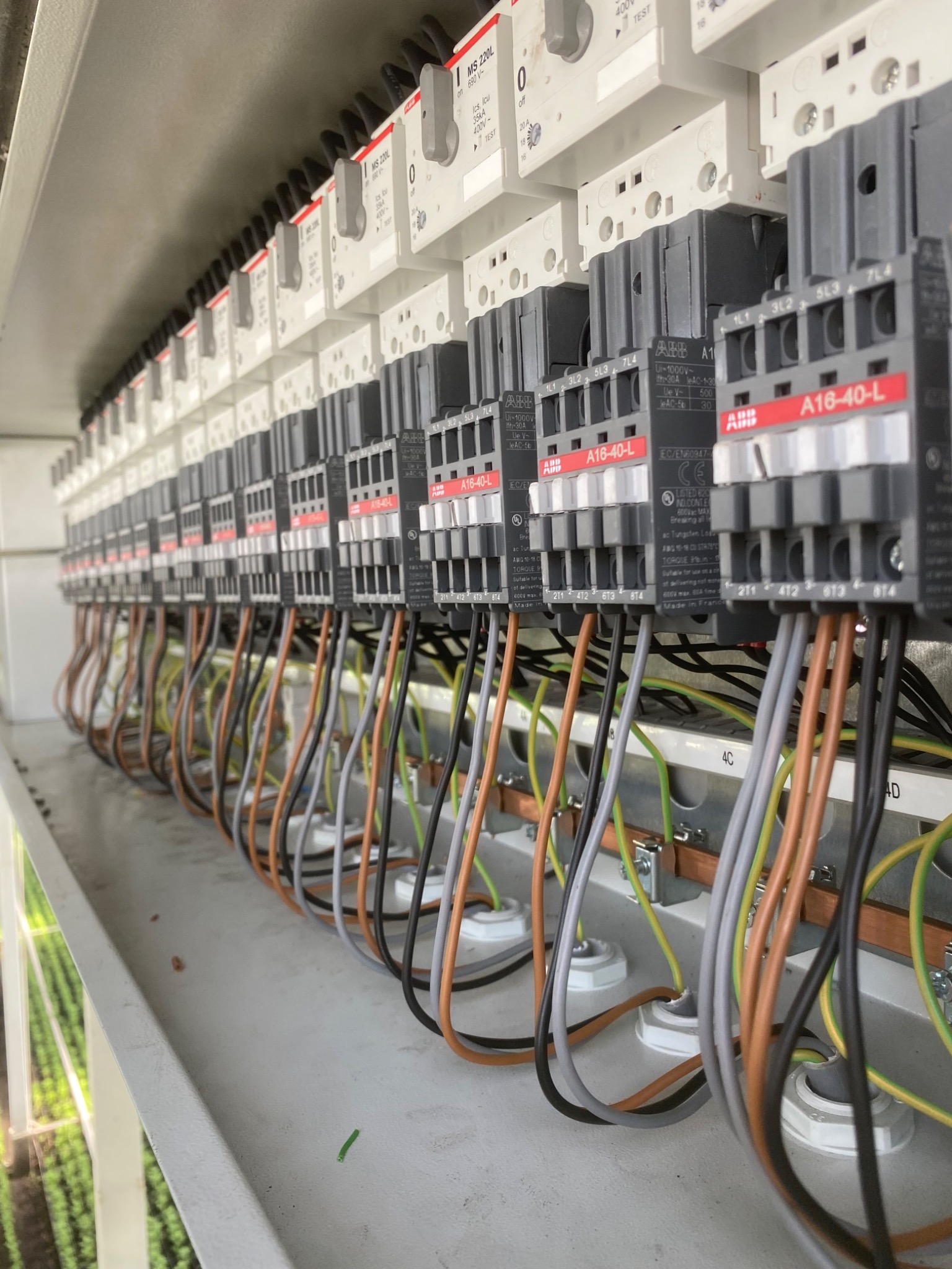 Rząd styczników ABB A16-40-L w rozdzielnicy elektrycznej, z widocznymi przewodami w kolorach brązowym, szarym i czarnym, podłączonymi do listwy zaciskowej.