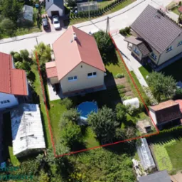 Zdjęcie z lotu ptaka przedstawiające dom jednorodzinny z ogrodem i basenem w Bartoszycach, granica działki oznaczona czerwoną linią.