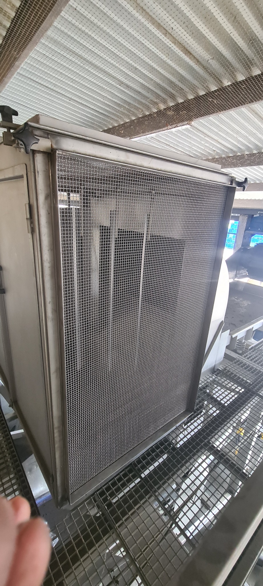 Metalowa obudowa z siatką ochronną, zamontowana na konstrukcji kratownicowej pod zadaszeniem, widoczne elementy mocujące.