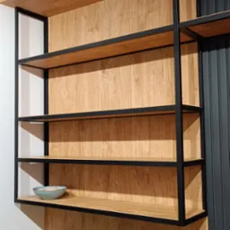 Półki z drewnianym wykończeniem i czarną metalową ramą, na jednej z nich stoi jasnoniebieska miseczka, a u dołu widoczna zielona roślina w doniczce.