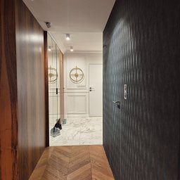 Katsiaryna Padasinavik - Elegancki korytarz po remoncie: parkiet w jodełkę, ciemna tapeta w pionowe pasy, lustro w zabudowie i marmurowe płytki w głębi. Nowoczesne oświetlenie.