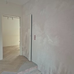Katsiaryna Padasinawik - Ściana z dekoracyjnym malowaniem chmur i ptaków w jasnym wnętrzu. Widoczny fragment podłogi i schodów w trakcie prac wykończeniowych. Nietypowe wykończenie ściany.