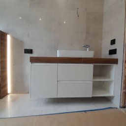 MEBS MARIUSZ SYC - Nowoczesna łazienka z białą szafką pod umywalkę z drewnianym blatem, minimalistyczna umywalka nablatowa, widoczne niedokończone wykończenia ściany z cegły.