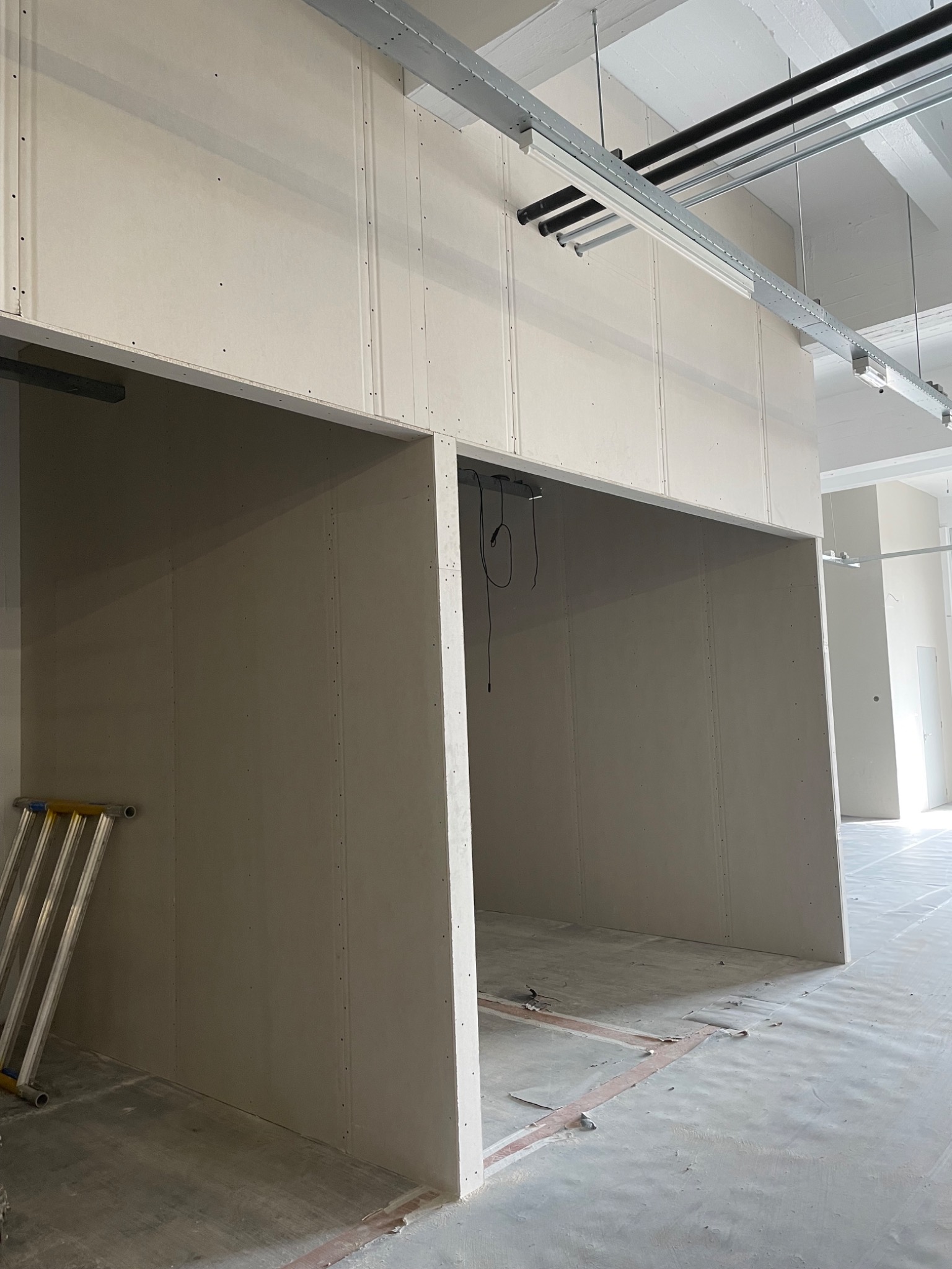 Montaż ścian działowych z płyt gipsowo-kartonowych w Olsztynie, widoczne metalowe profile pod sufitem i drabina oparta o ścianę.