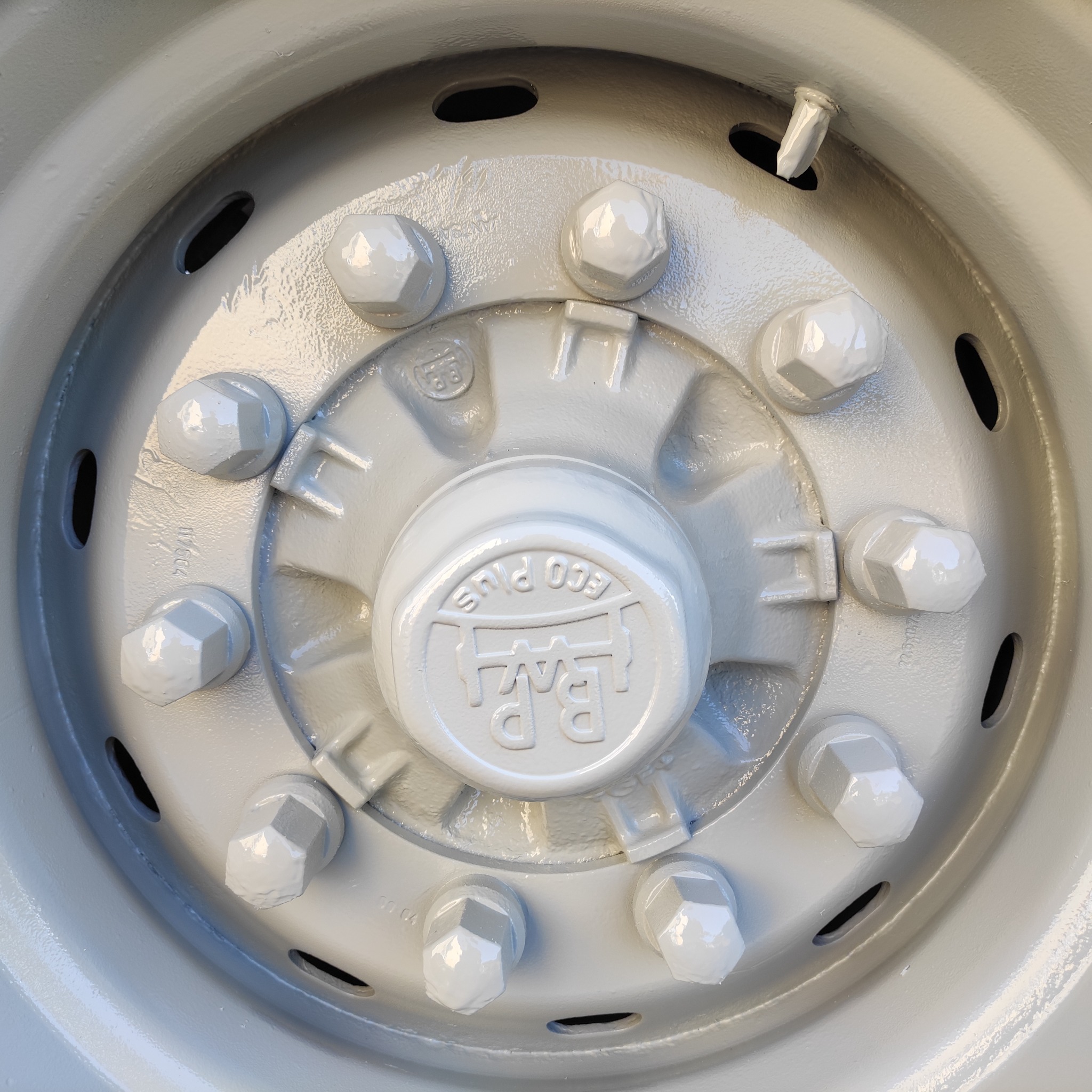 Szare koło z centralną piastą z logo B.P. ECO PLUS, zabezpieczone śrubami, widoczne otwory wentylacyjne w obręczy.