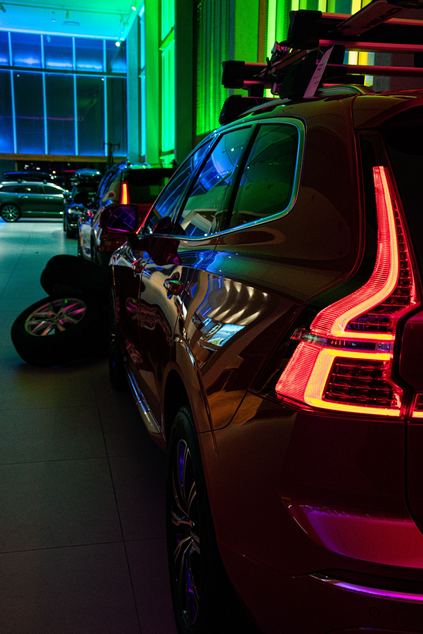 Czerwony samochód Volvo XC60 z bagażnikiem dachowym na narty w salonie samochodowym, widok na tylne światło i opony obok.