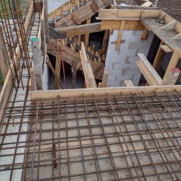Centra - Zbrojenie płyty fundamentowej z deskowaniem i częściowo wymurowanymi ścianami z betonu komórkowego w tle.