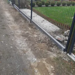 Fragment nowo postawionego ogrodzenia panelowego z podmurówką betonową w Kartuzach, widok z zewnątrz posesji, teren wokół ogrodzenia częściowo uporządkowany.