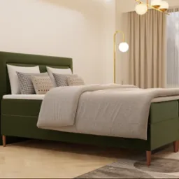 Ł&oacute;żko kontynentalne z zielonym tapicerowanym wezgłowiem i beżową narzutą, ustawione na parkiecie w jasnym wnętrzu z zasłonami i lampą podłogową.