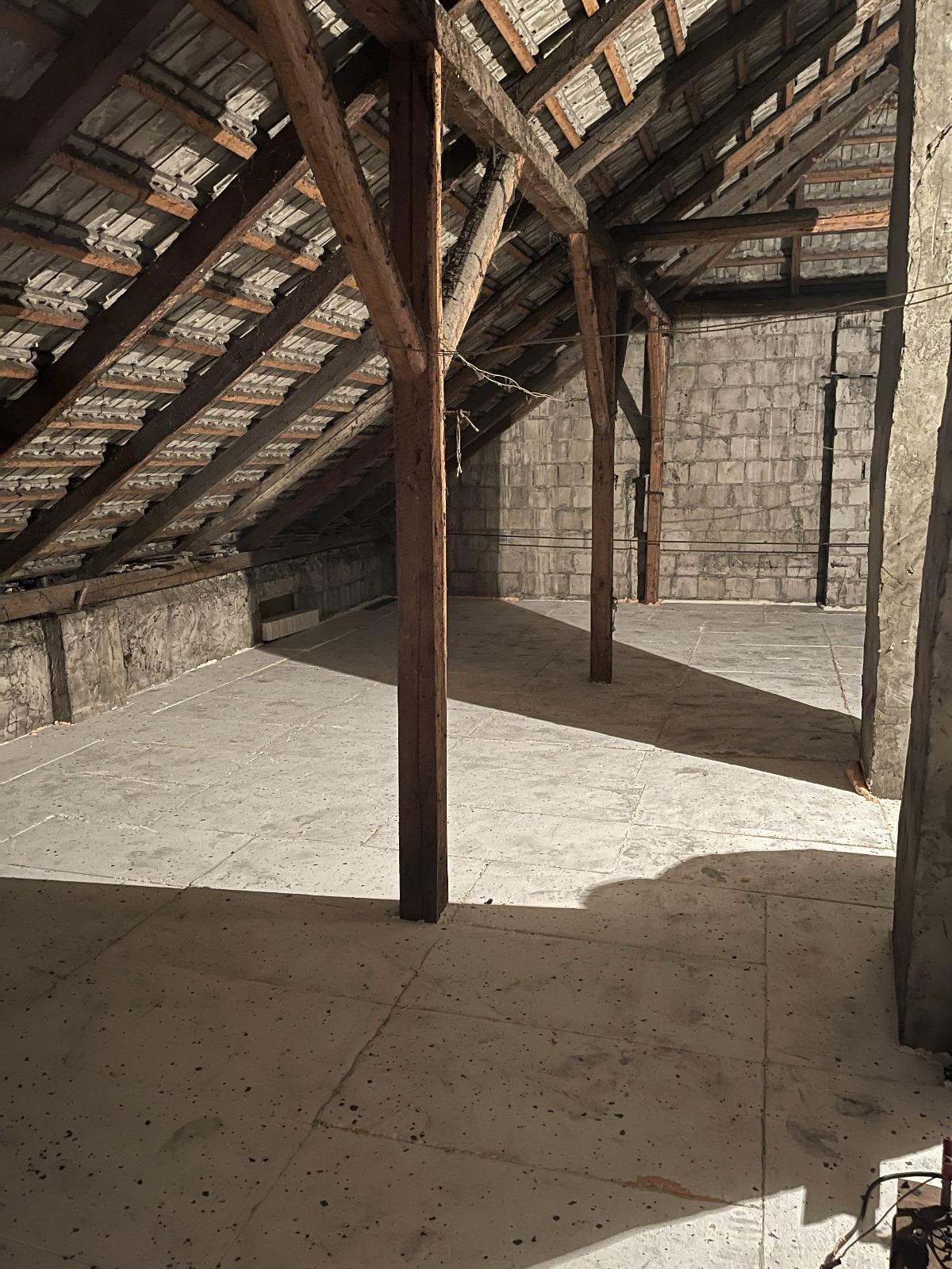 Poddasze z drewnianą konstrukcją dachu, ocieplone płytami, widoczne elementy muru z bloczków betonowych.