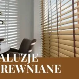 Beżowe żaluzje drewniane z ciemnobrązowymi taśmami, zamontowane w jasnym wnętrzu. Na parapecie dekoracja z gałązek kwitnącej rośliny.