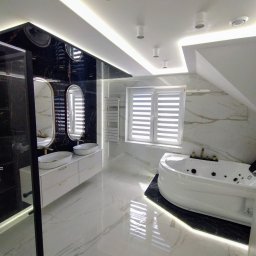 PCmedia24 Szczepan Jasiński - Nowoczesna łazienka na poddaszu z wanną z hydromasażem, umywalkami nablatowymi i kabiną prysznicową typu walk-in, wykończona marmurem i podświetleniem LED.