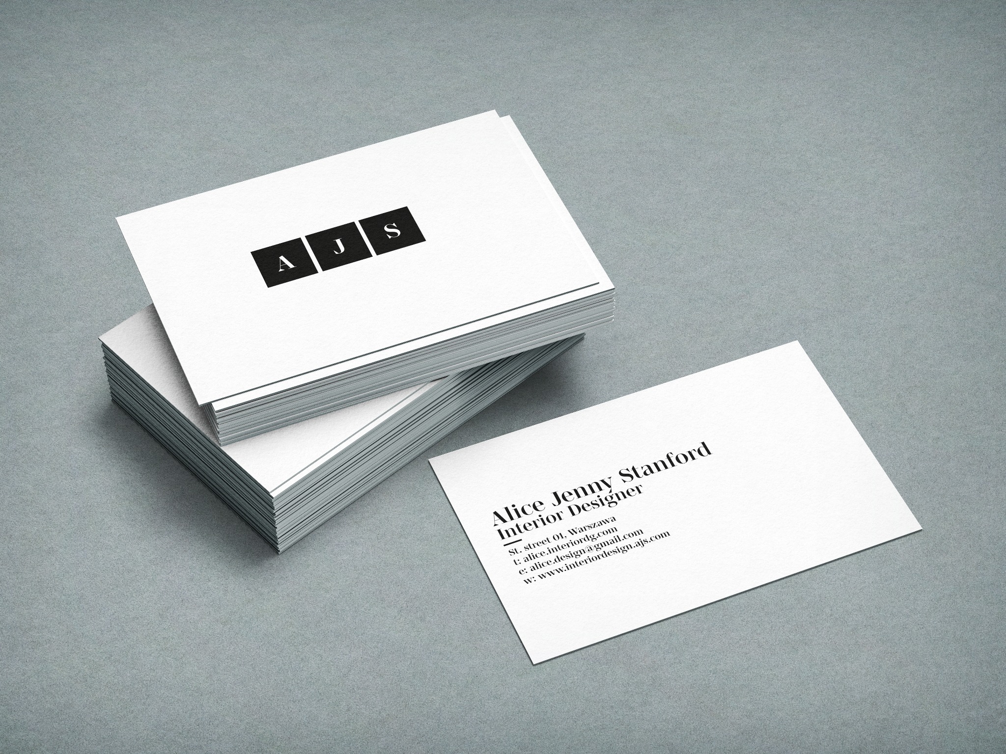 Stos wizytówek z minimalistycznym projektem logo 'AJS' w czarnych kwadratach, obok pojedyncza wizytówka z danymi projektantki wnętrz Alice Jenny Stanford, na szarym tle.