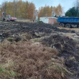 Teren po wycince drzew z widocznym koparką i wywrotką, przygotowany pod budowę.