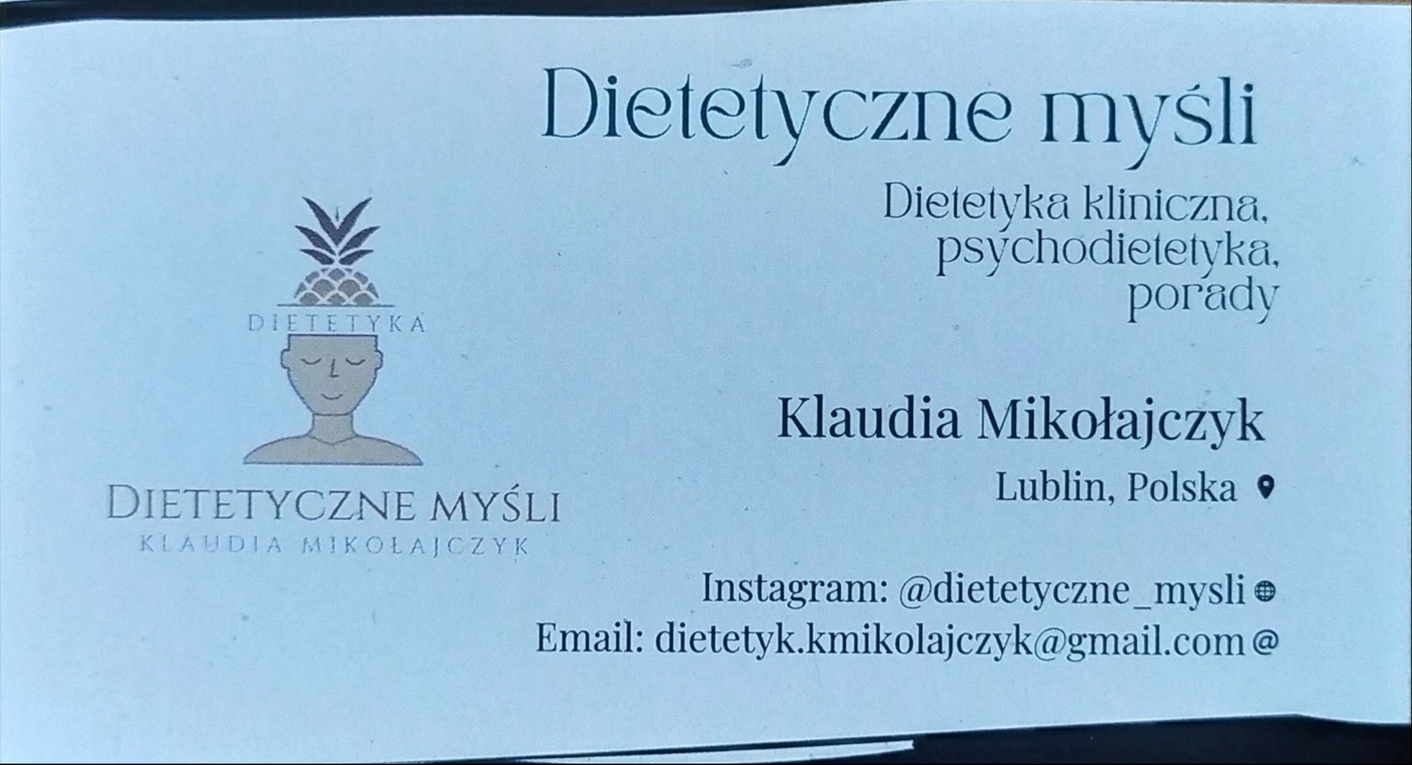 Wizytówka z logo i danymi kontaktowymi gabinetu dietetycznego: Dietetyczne Myśli, Klaudia Mikołajczyk, Lublin, adres email i Instagram. Logo przedstawia głowę z ananasem.