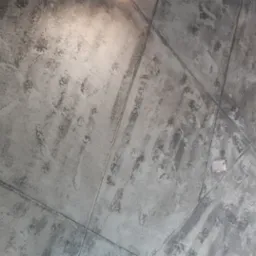 Ściana pokryta szarą gładzią dekoracyjną imitującą efekt betonu, podzielona na kwadraty delikatnymi wgłębieniami, oświetlona punktowo.