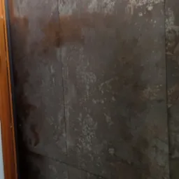 Ściana wykończona płytami imitującymi rdzę, z widocznymi łączeniami i oświetleniem LED u góry.