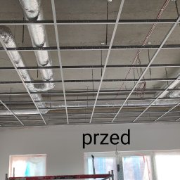 KADRA SPÓŁKA Z OGRANICZONĄ ODPOWIEDZIALNOŚCIĄ - Montaż metalowego rusztu sufitu podwieszanego z widocznymi przewodami wentylacyjnymi i instalacją elektryczną przed zakryciem płytami gipsowymi.