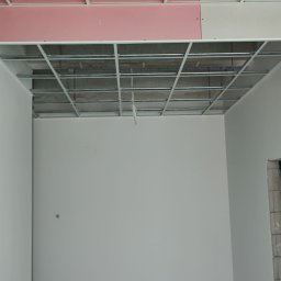 KADRA SPÓŁKA Z OGRANICZONĄ ODPOWIEDZIALNOŚCIĄ - Wnętrze w trakcie remontu: widoczne ściany po nałożeniu warstwy wykończeniowej i stelaż podwieszanego sufitu z płyt kartonowo-gipsowych, widok 'przed' dalszymi pracami.