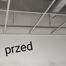 KADRA SPÓŁKA Z OGRANICZONĄ ODPOWIEDZIALNOŚCIĄ - Sufit podwieszany kasetonowy z widoczną instalacją wentylacyjną przed montażem paneli, na ścianie napis 'przed'.