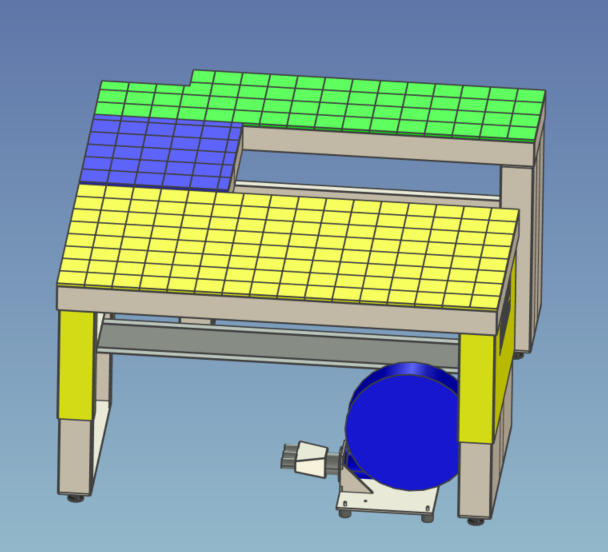Model 3D stanowiska roboczego z blatem podzielonym na żółte, zielone i niebieskie kwadraty, widoczny niebieski silnik z osprzętem u podstawy.