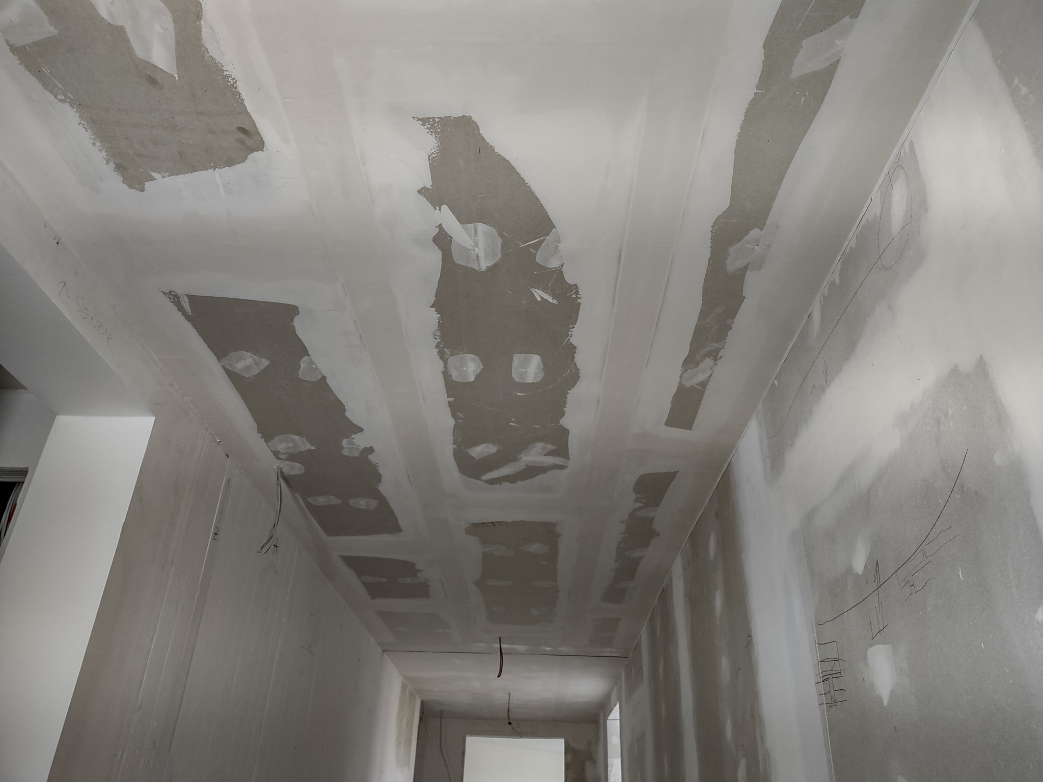 Sufit i ściany w trakcie szpachlowania płyt karton-gips, widoczne łączenia płyt wypełnione masą szpachlową, surowe wykończenie wnętrza.