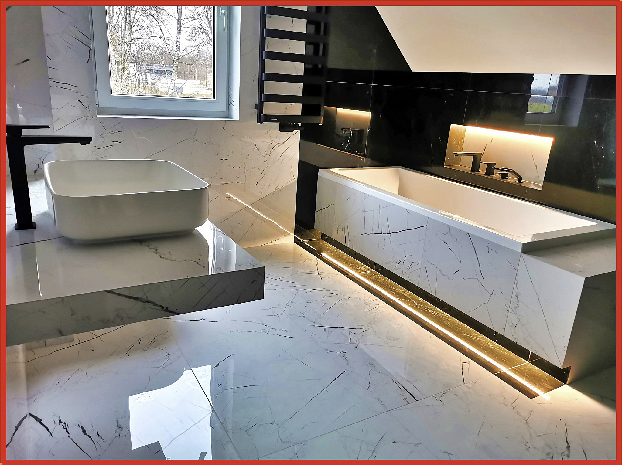 Nowoczesna łazienka z białymi płytkami imitującymi marmur, czarną armaturą i oświetleniem LED pod wanną.