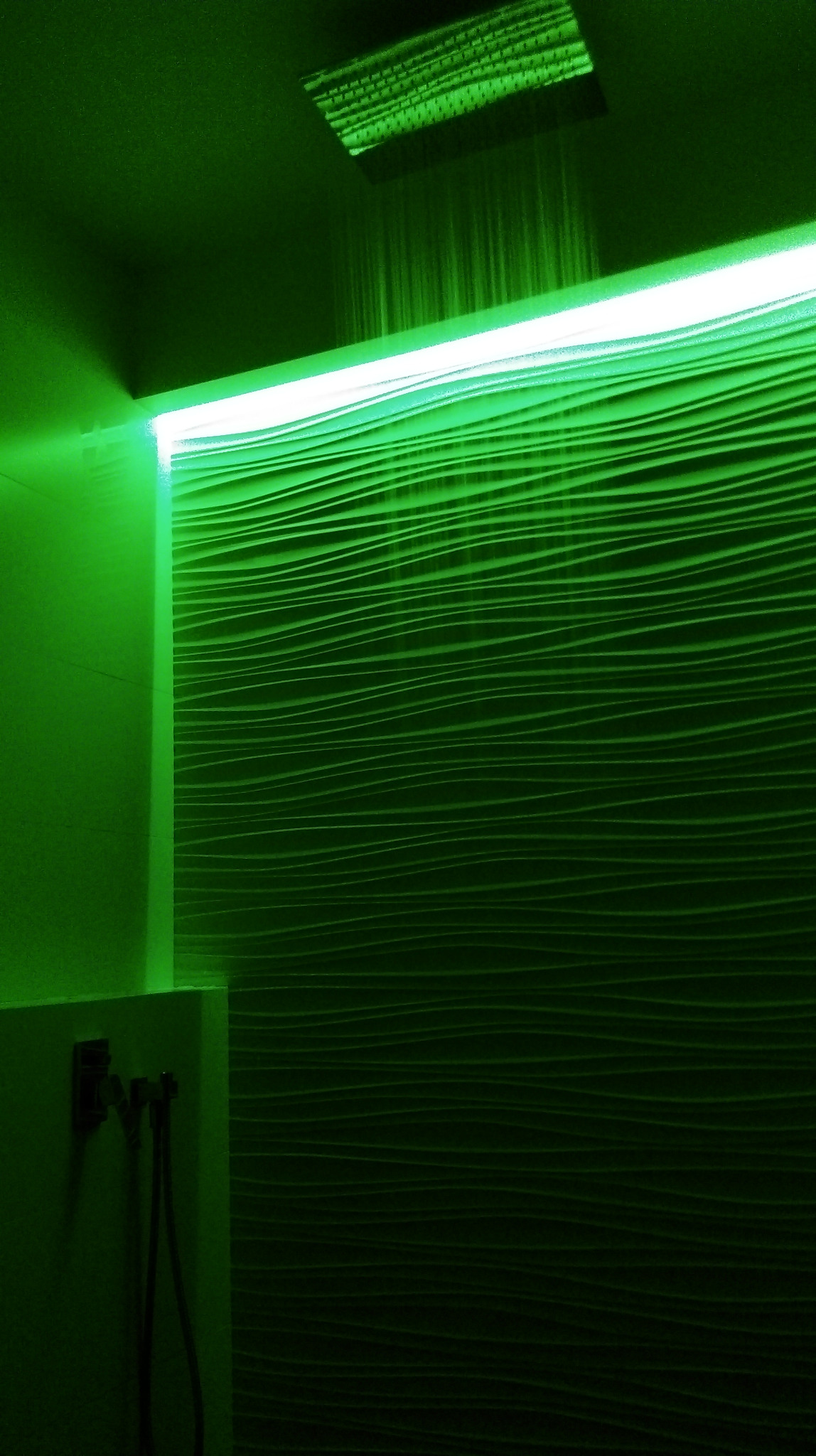 Nowoczesna kabina prysznicowa z deszczownicą i podświetleniem LED w odcieniach zieleni, ściana z dekoracyjną fakturą fal.