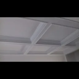 Biały sufit z dekoracyjnymi kwadratowymi panelami i listwami, widok z dołu pod kątem.