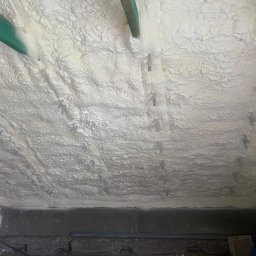 Thermo System - Poddasze ocieplone pianką PUR, widoczne metalowe elementy mocujące oraz drewniana belka stropowa w kolorze zielonym.