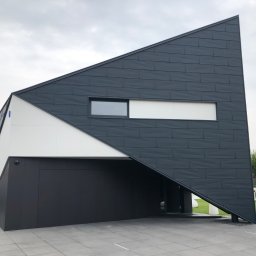 NOWE WNĘTRZE SPÓŁKA Z OGRANICZONĄ ODPOWIEDZIALNOŚCIĄ SPÓŁKA KOMANDYTOWA - Nowoczesny dom jednorodzinny z elewacją w kolorze antracytu, o nietypowej, trójkątnej bryle, z białymi akcentami i dużymi oknami, otoczony zadbanym ogrodem.