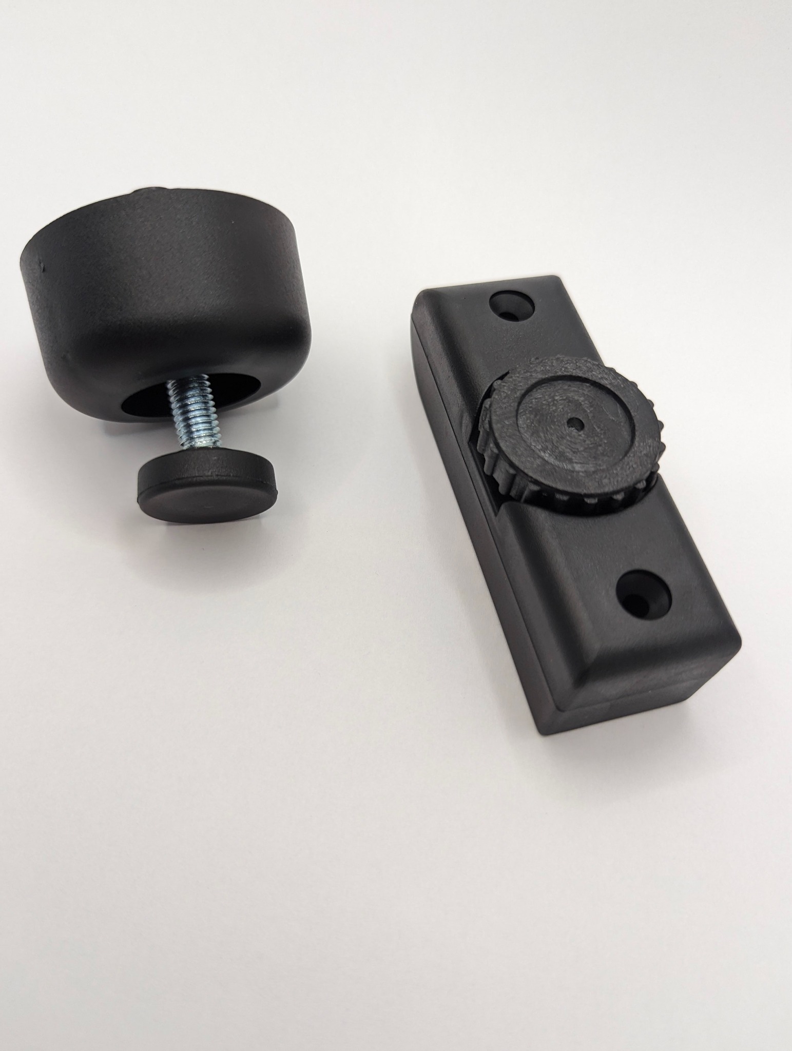Dwa czarne, plastikowe elementy: regulowana stopka z gwintem i element z pokrętłem regulacyjnym, oba prawdopodobnie wykonane metodą obróbki CNC, leżące na białym tle.