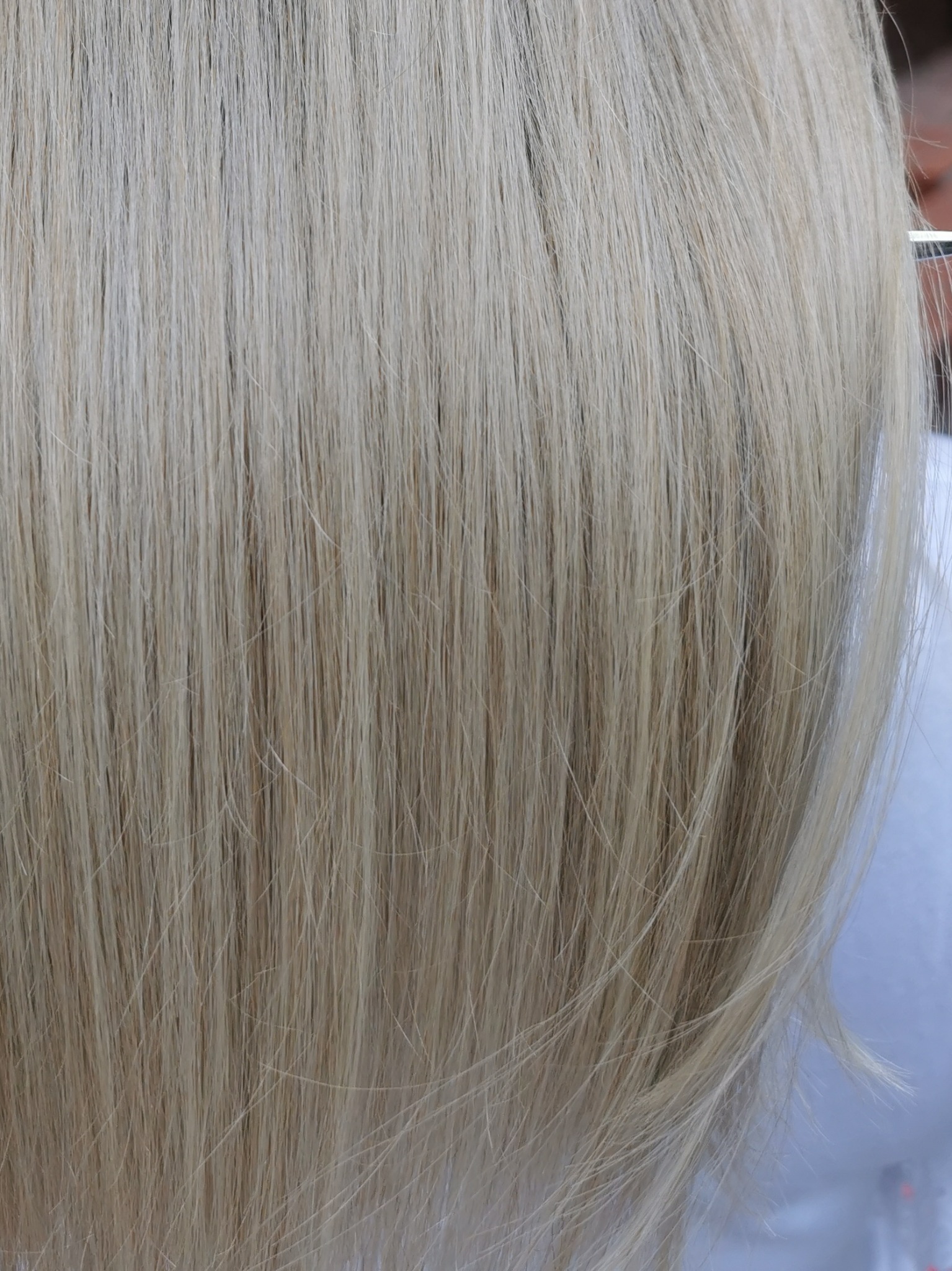 Jasne, proste włosy w odcieniach blondu, widoczne pojedyncze pasma, delikatne cieniowanie.