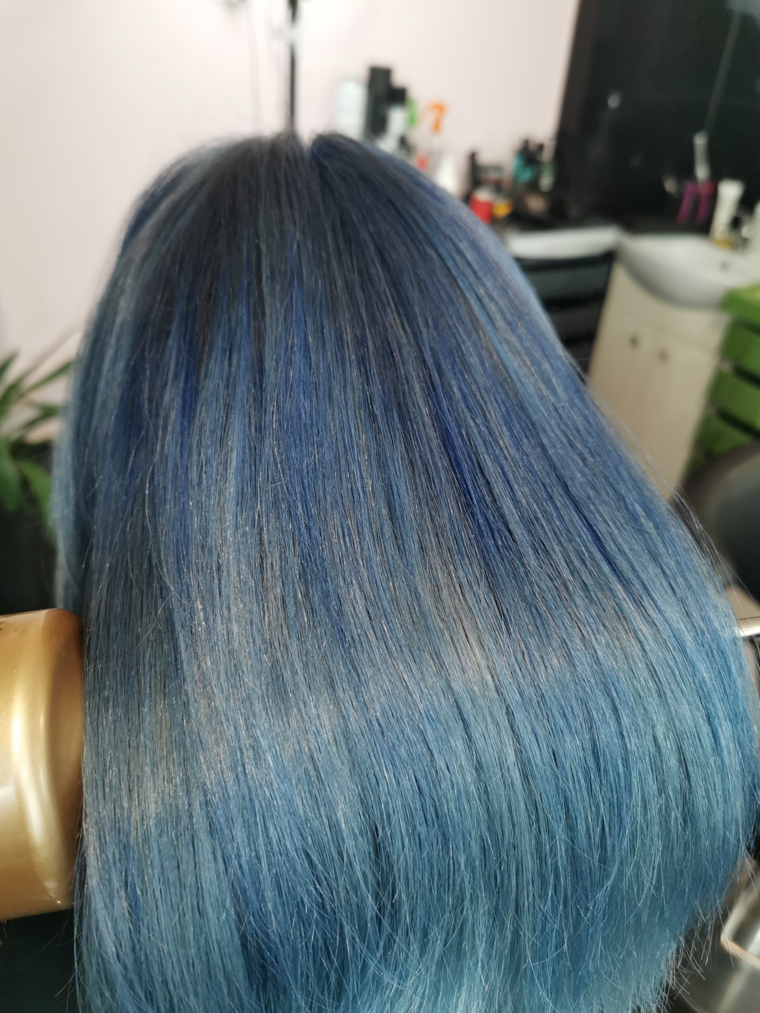 Włosy klientki w odcieniach granatu i błękitu, stylizowane lokówką w salonie fryzjerskim.